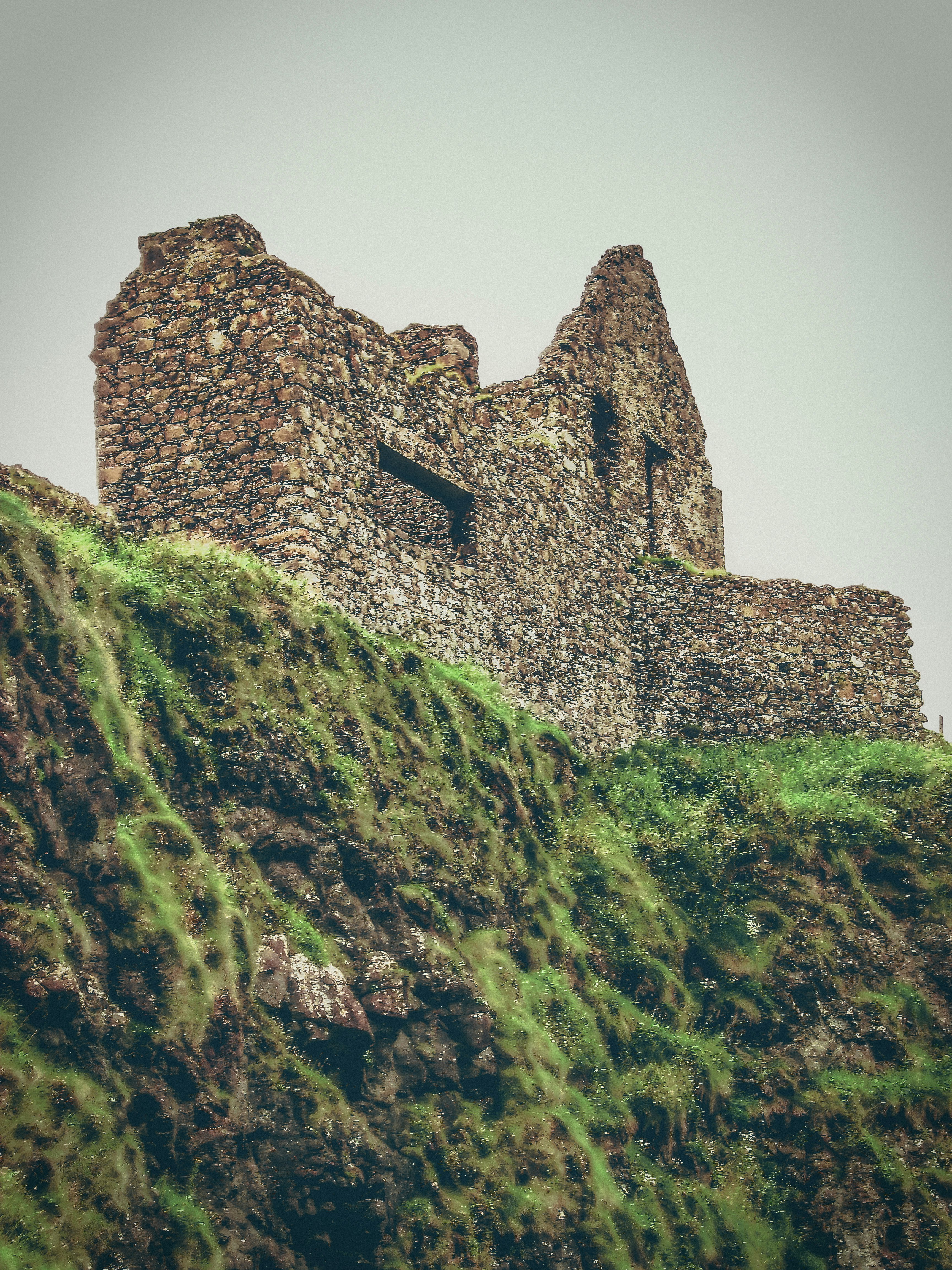 low-angle photography of gray rocky house on cliff